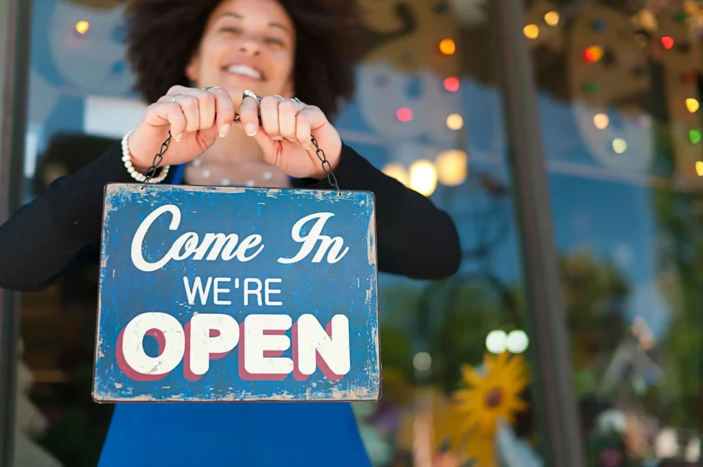 Woman with Open Sign outside of a boutique store front