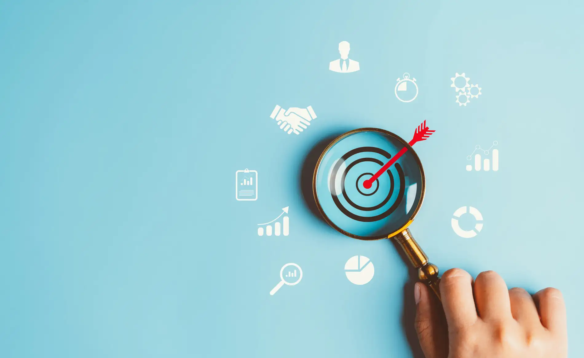 Hand holding magnifying glass zooming in on red arrow hitting bullseye target, symbolizing target marketing strategy, surrounded by business icons like graphs, charts, handshake, gears, and clock