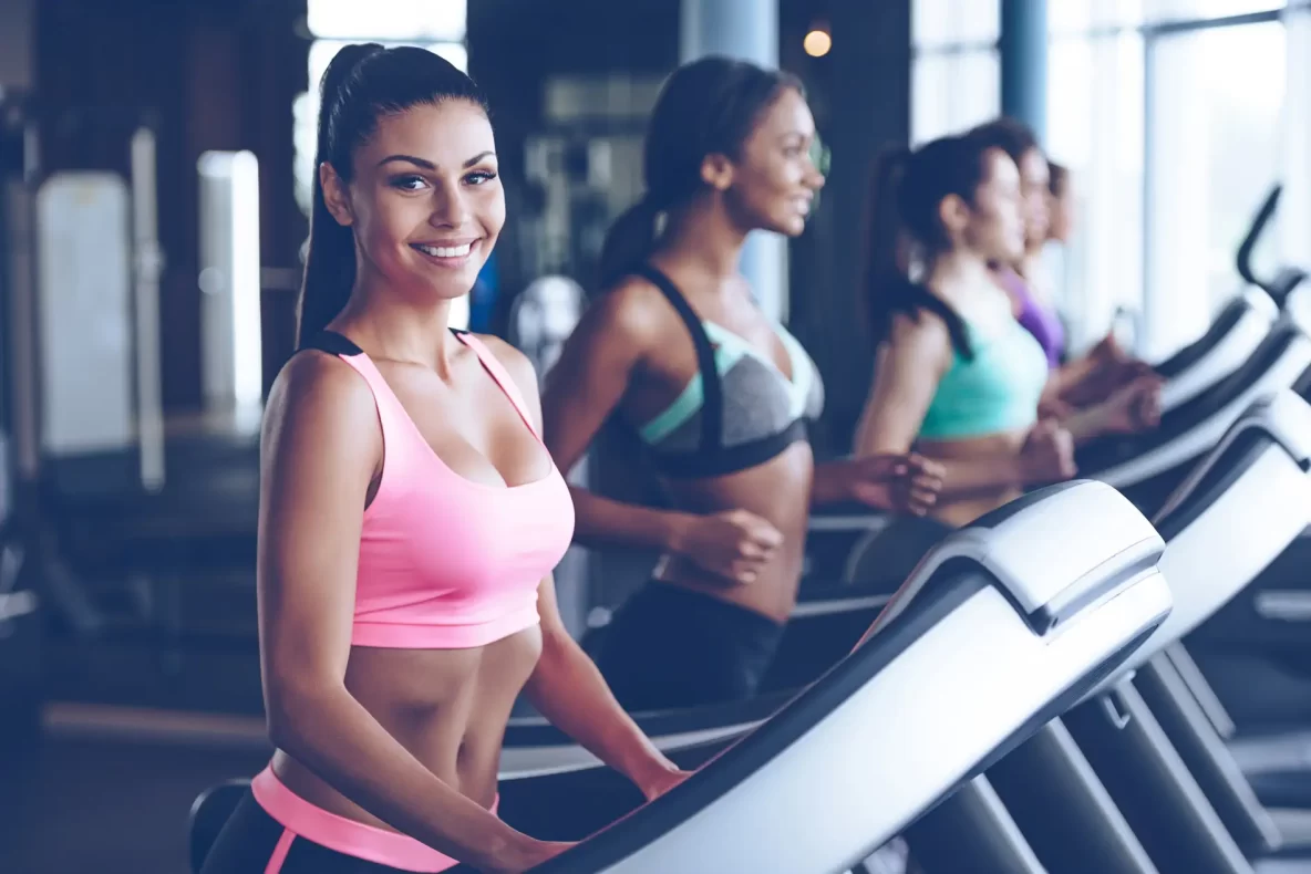 Women running on a treadmill in a gym.