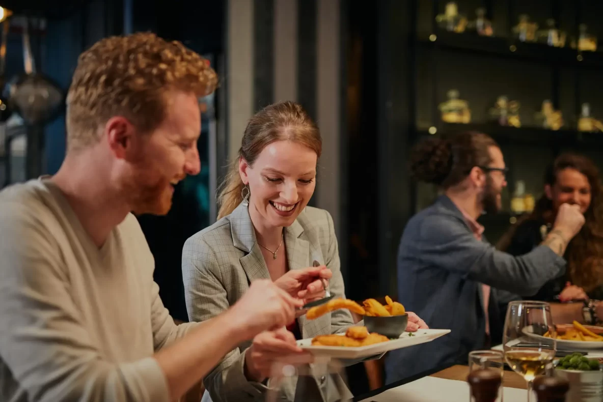 A happy couple dining at a restaurant sharing an appetizer.