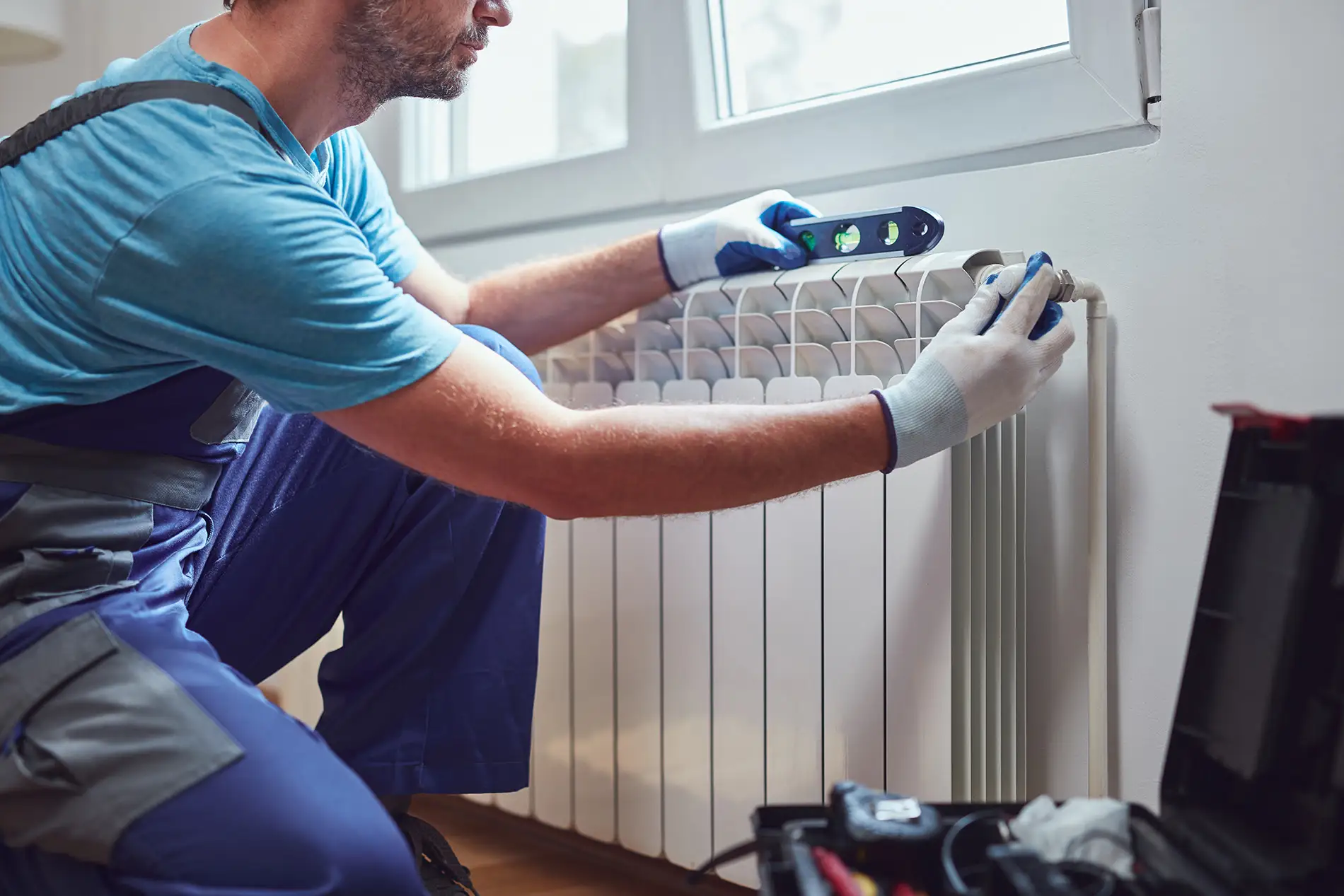 HVAC mechanic fixing a radiator in a home.