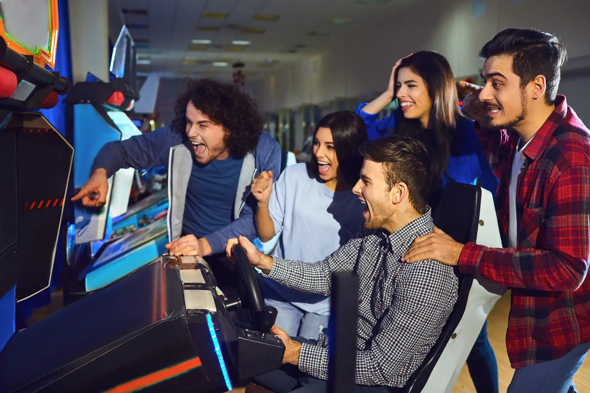 Group of adults cheering playing games at an arcade.