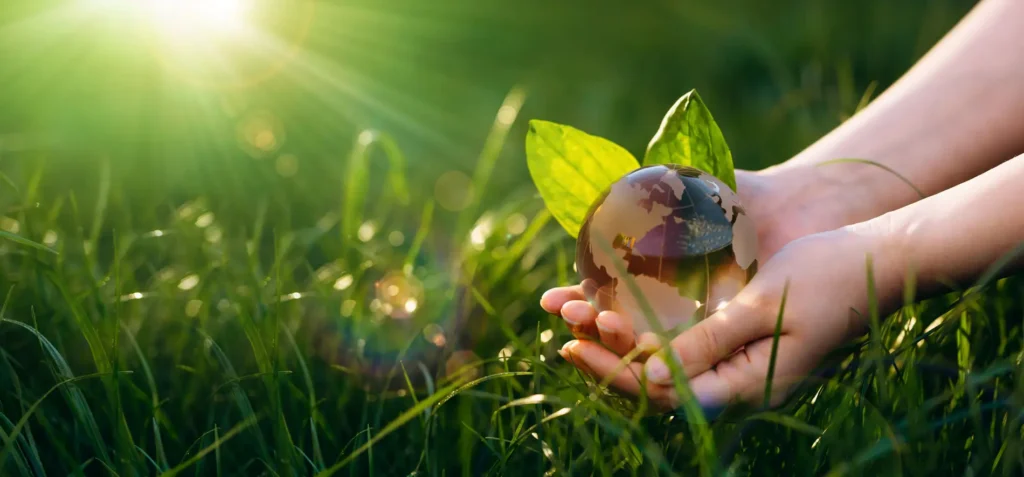 Crystal Earth globe held in human hands illustrating Earth Day, ecology, and the importance of protecting a clean planet.